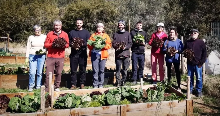 A l'Hort de la Sínia uns participants amb enciams i cols a les mans